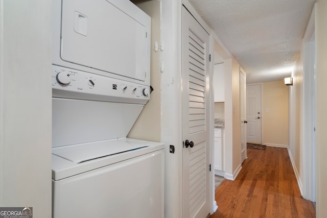 3301 Henderson Mill Rd Unit J1, Atlanta, GA 30341 - laundry area featuring stacked washer / dryer, a textured ceiling, light wood finished floors, and baseboards