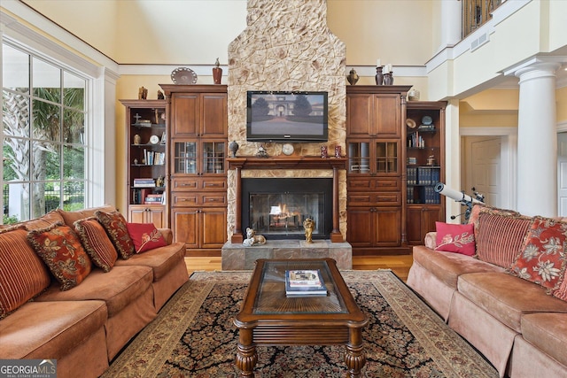 19410 Ga Highway 169, Claxton, GA 30417 - living area featuring a premium fireplace, a towering ceiling, light wood-type flooring, and decorative columns