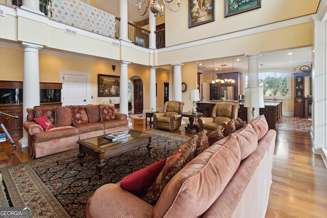 19410 Ga Highway 169, Claxton, GA 30417 - living room featuring a chandelier, decorative columns, wood finished floors, a towering ceiling, and baseboards