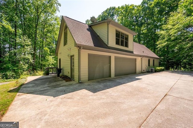 465 Willowbrook Dr, Smyrna, GA 30082 - view of side of home with concrete driveway, a shingled roof, an attached garage, and central AC