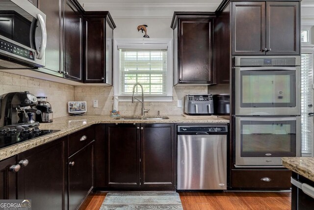 110 Bluegrass Cir, Guyton, GA 31312 - kitchen with appliances with stainless steel finishes, a sink, light stone countertops, decorative backsplash, and crown molding