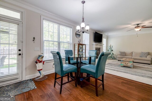 110 Bluegrass Cir, Guyton, GA 31312 - dining area with a chandelier, crown molding, dark wood-type flooring, baseboards, and a tile fireplace