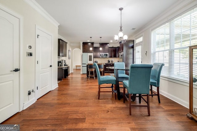 110 Bluegrass Cir, Guyton, GA 31312 - dining space featuring ornamental molding, a chandelier, dark wood finished floors, baseboards, and arched walkways