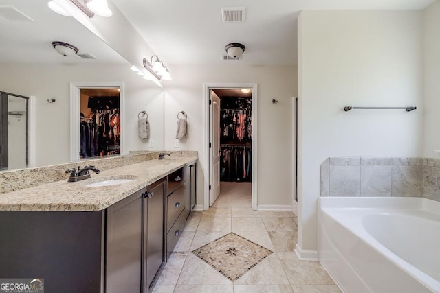 110 Bluegrass Cir, Guyton, GA 31312 - bathroom featuring a garden tub, baseboards, double vanity, and a walk in closet