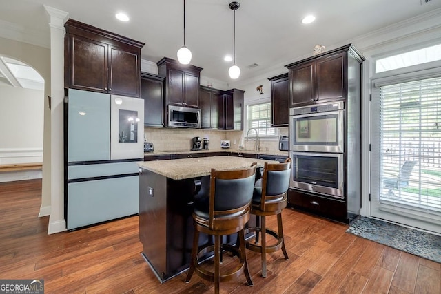110 Bluegrass Cir, Guyton, GA 31312 - kitchen featuring stainless steel appliances, dark brown cabinets, ornamental molding, tasteful backsplash, and a center island