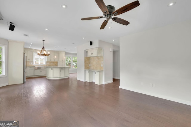 unfurnished living room with baseboards, dark wood-type flooring, a ceiling fan, recessed lighting, and a chandelier