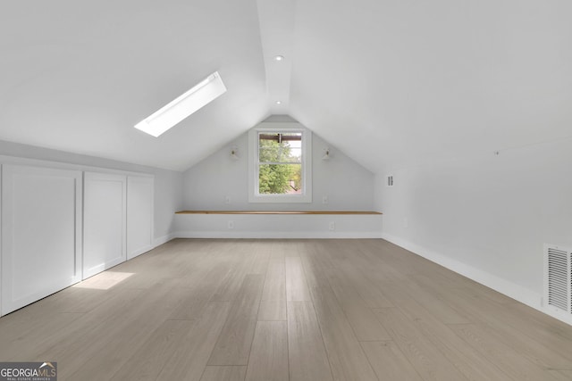 bonus room featuring a skylight, light wood-style flooring, lofted ceiling, and baseboards