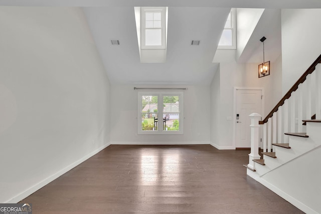 foyer entrance with stairway, dark wood-style floors, high vaulted ceiling, baseboards, and a chandelier