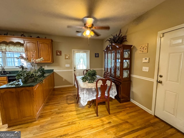dining space featuring light wood-type flooring, a ceiling fan, and baseboards