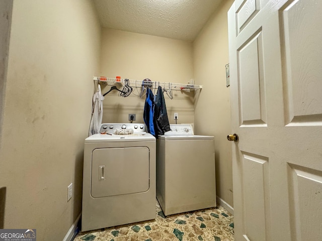 laundry area with independent washer and dryer, a textured ceiling, and baseboards
