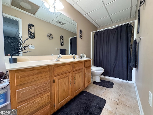 full bath with tile patterned floors, vanity, toilet, a paneled ceiling, and baseboards