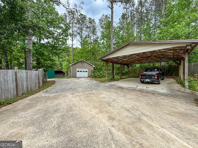 view of parking / parking lot with concrete driveway, fence, and view of wooded area