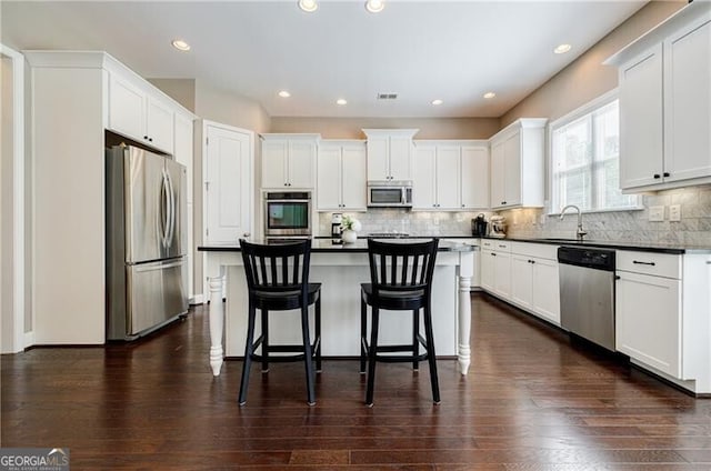 468 Scott Farm Dr, Powder Springs, GA 30127 - kitchen with stainless steel appliances, dark countertops, a kitchen bar, dark wood finished floors, and recessed lighting