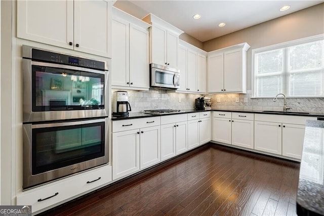 468 Scott Farm Dr, Powder Springs, GA 30127 - kitchen featuring appliances with stainless steel finishes, a sink, white cabinets, dark countertops, and decorative backsplash