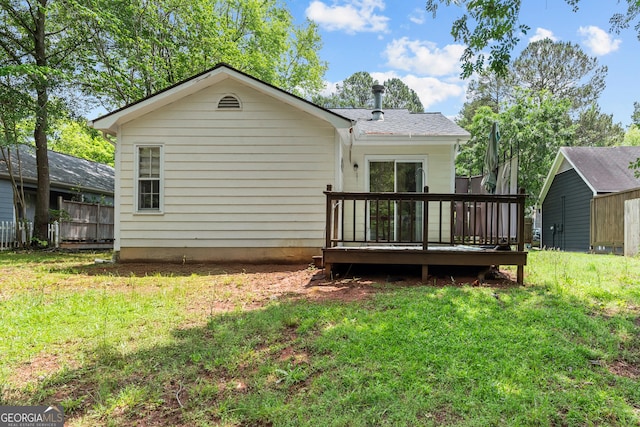 rear view of property featuring a deck and a lawn