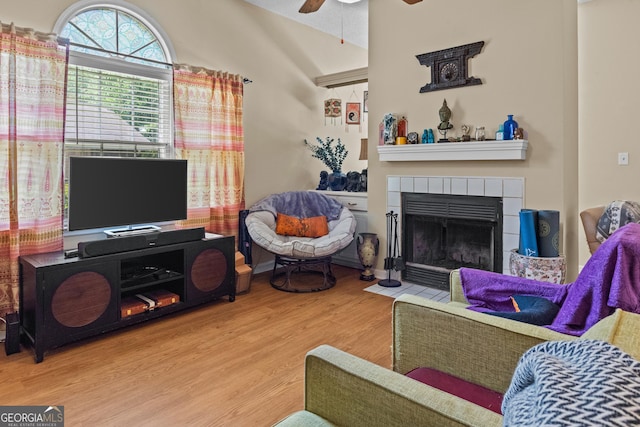 living room with wood finished floors, ceiling fan, and a tile fireplace
