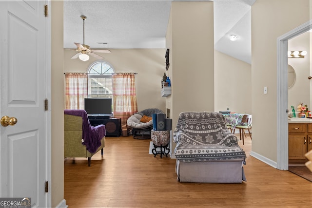 living area with wood finished floors and ceiling fan