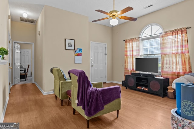 living room with wood finished floors, a ceiling fan, and baseboards