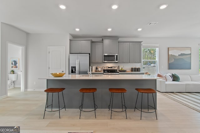 3142 Washburn St, Atlanta, GA 30354 - kitchen with stainless steel appliances, a sink, gray cabinetry, a kitchen island with sink, and a kitchen bar