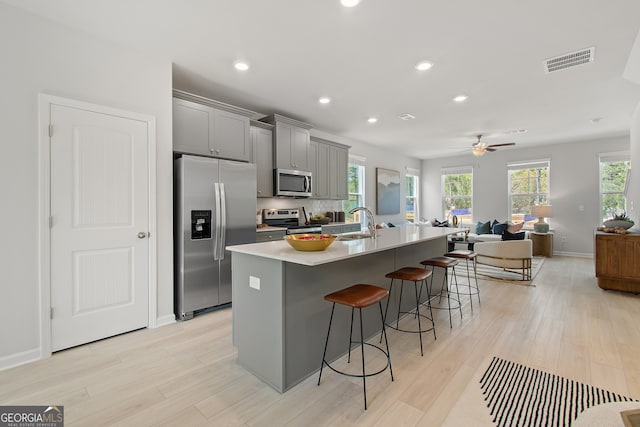 3142 Washburn St, Atlanta, GA 30354 - kitchen featuring appliances with stainless steel finishes, gray cabinets, light wood-style floors, a breakfast bar, and an island with sink