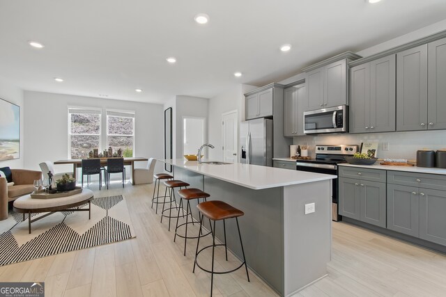 3142 Washburn St, Atlanta, GA 30354 - kitchen with stainless steel appliances, gray cabinetry, a sink, a kitchen bar, and a kitchen island with sink