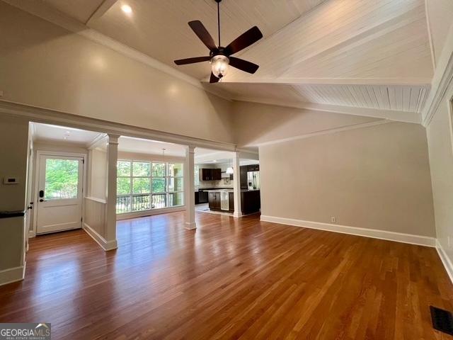 617 Smith St S, Bremen, GA 30110 - unfurnished living room with lofted ceiling, ceiling fan, ornate columns, baseboards, and wood finished floors