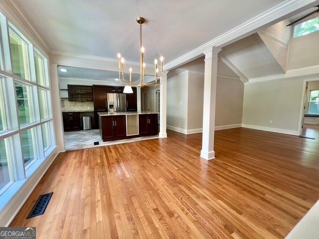 617 Smith St S, Bremen, GA 30110 - unfurnished dining area featuring a chandelier, light wood-style flooring, baseboards, decorative columns, and crown molding