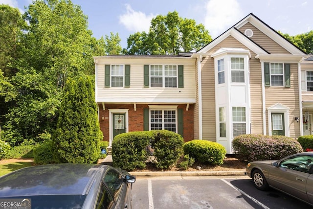 townhome / multi-family property featuring uncovered parking and brick siding