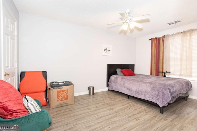 bedroom featuring wood finished floors, baseboards, and a ceiling fan