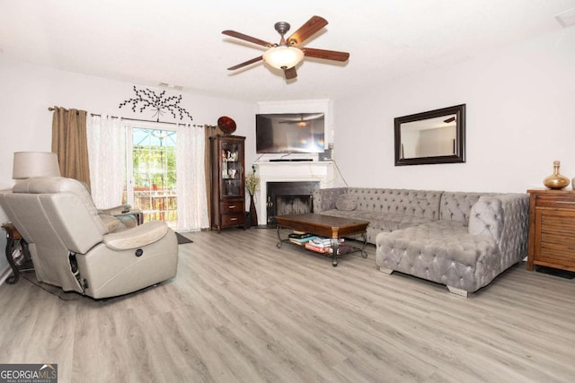 living area featuring wood finished floors, a fireplace, and a ceiling fan
