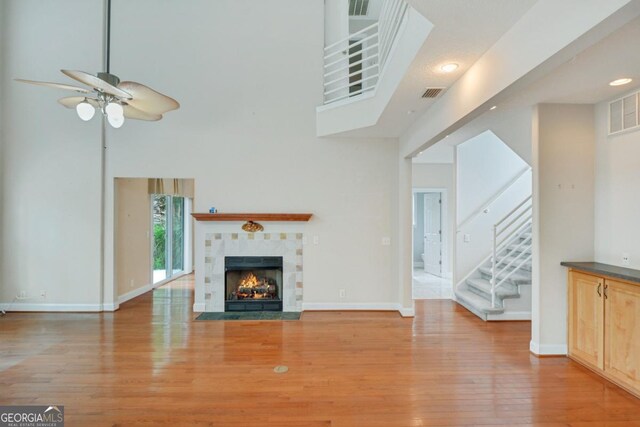 175 Palmera Ln, Brunswick, GA 31525 - unfurnished living room with wood finished floors, ceiling fan, stairway, a tile fireplace, and baseboards