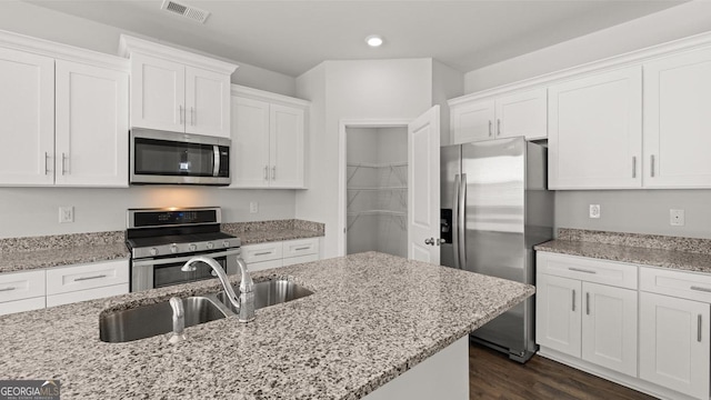 kitchen featuring stainless steel appliances, a sink, white cabinets, recessed lighting, and light stone counters
