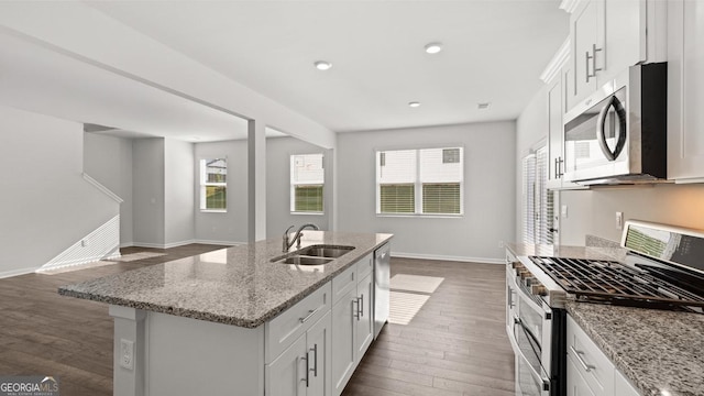 kitchen featuring appliances with stainless steel finishes, a sink, dark wood-style floors, baseboards, and white cabinets