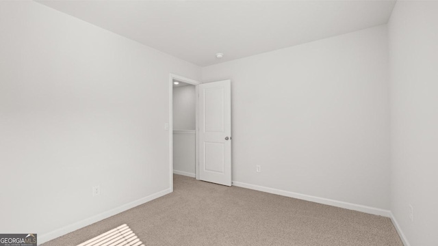 empty room featuring light carpet and baseboards