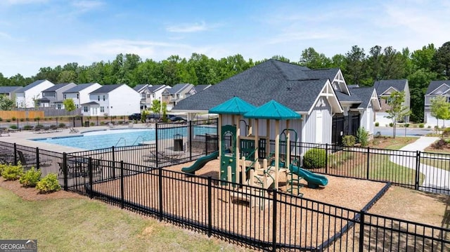 community jungle gym featuring fence, a residential view, and a community pool