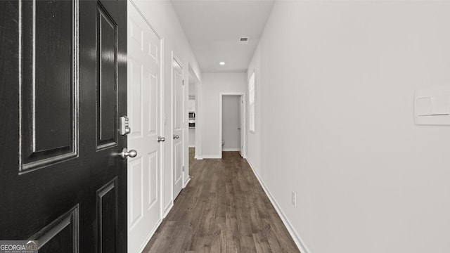 corridor with dark wood finished floors, baseboards, and recessed lighting