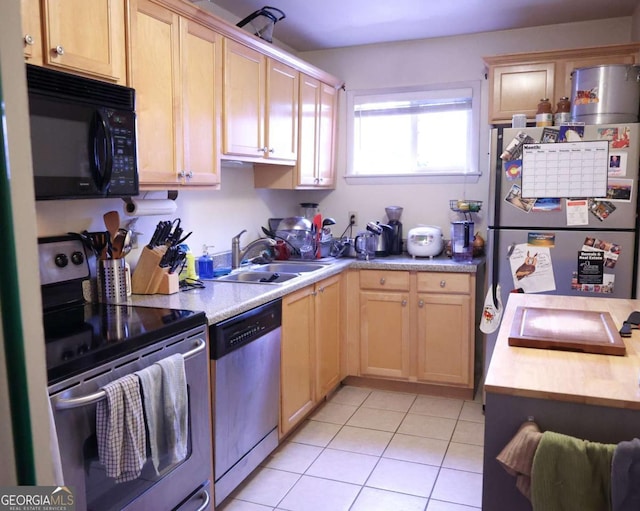 kitchen featuring appliances with stainless steel finishes, light tile patterned floors, a sink, and light countertops