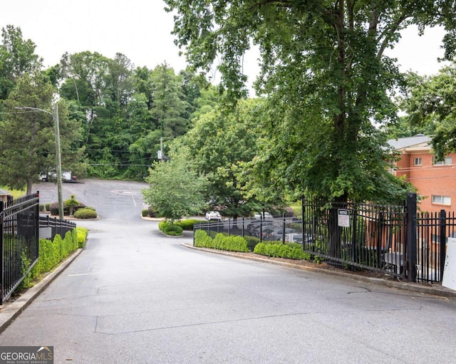 view of asphalt road featuring street lighting, a gated entry, and curbs