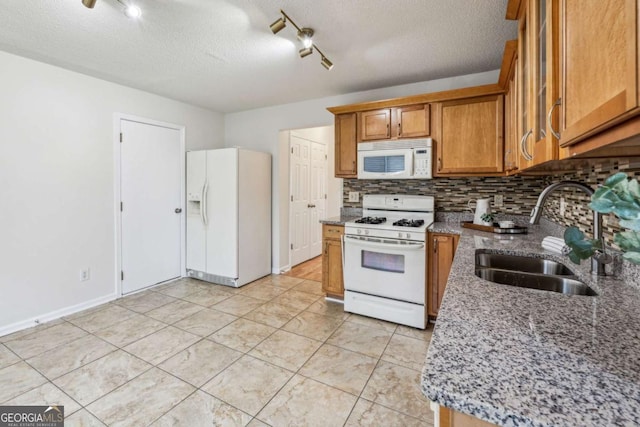 kitchen with white appliances, a sink, backsplash, a textured ceiling, and brown cabinetry