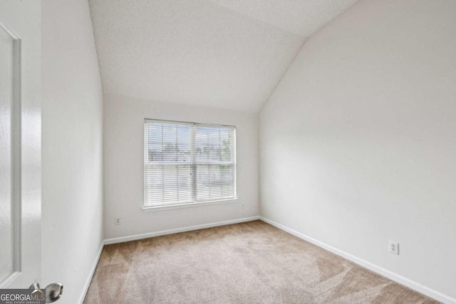 carpeted empty room with lofted ceiling and baseboards