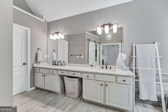 bathroom with lofted ceiling, double vanity, and wood finished floors