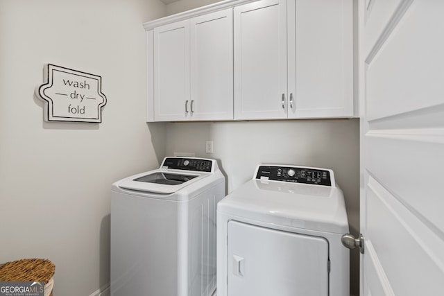 clothes washing area featuring washing machine and clothes dryer and cabinet space