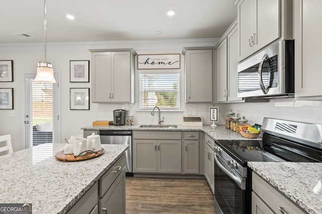 kitchen featuring stainless steel appliances, a sink, gray cabinets, crown molding, and decorative backsplash
