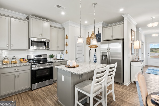 kitchen with stainless steel appliances, gray cabinets, dark wood-type flooring, ornamental molding, and recessed lighting