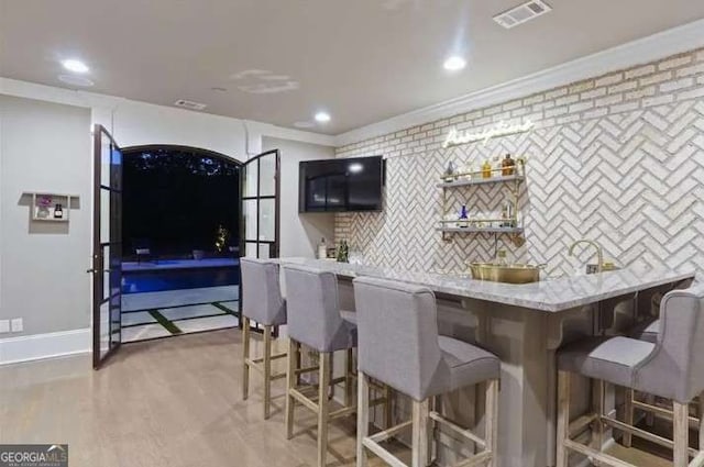 2242 Shoal Creek Rd, Buford, GA 30518 - kitchen featuring crown molding, a breakfast bar, tasteful backsplash, recessed lighting, and light stone countertops