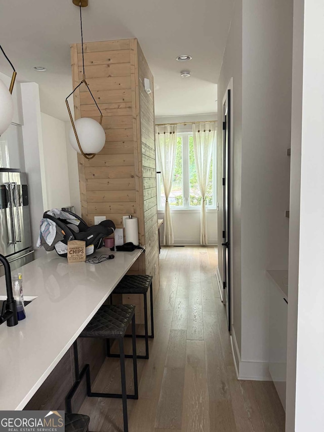 corridor featuring hardwood / wood-style flooring, baseboards, and wooden walls