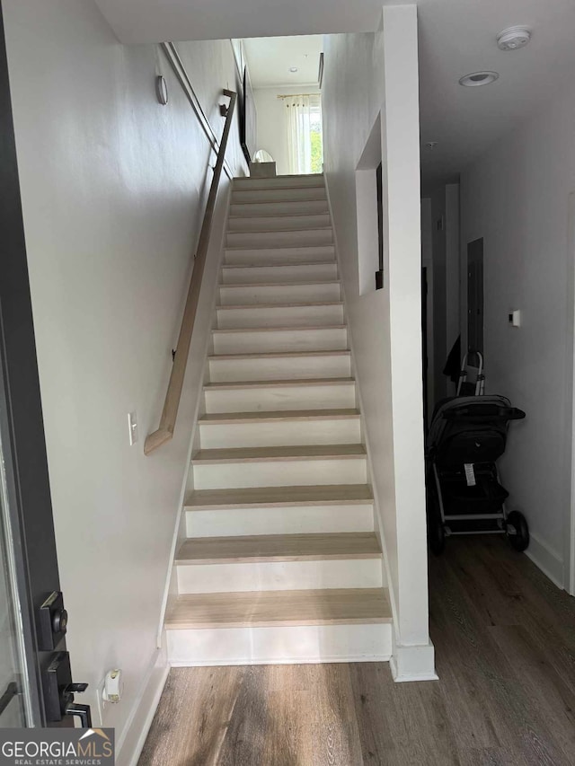 staircase featuring wood finished floors and baseboards