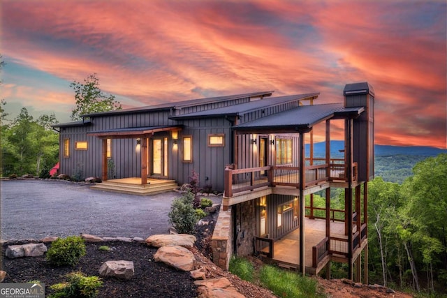 885 Tower Rd, Mineral Bluff, GA 30559 - back of property at dusk with board and batten siding, a chimney, and a deck