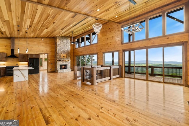 885 Tower Rd, Mineral Bluff, GA 30559 - unfurnished living room with high vaulted ceiling, wood walls, wood ceiling, light wood finished floors, and a stone fireplace