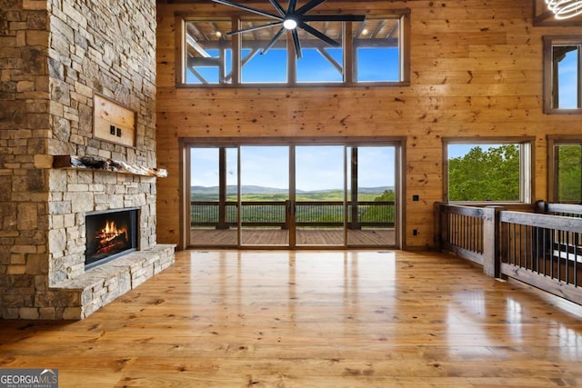 885 Tower Rd, Mineral Bluff, GA 30559 - unfurnished living room featuring a towering ceiling, hardwood / wood-style flooring, a fireplace, wood walls, and a mountain view